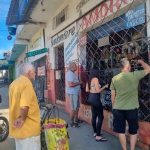 Compra com barreira: consumidores esperam na calçada e comerciante fica atrás de proteção metálica após o segundo assalto. Pesquisa mostra que medidas do tipo incomodam clientes -  (crédito: Luiz Ribeiro/EM/D.A Press)