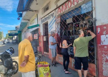 Compra com barreira: consumidores esperam na calçada e comerciante fica atrás de proteção metálica após o segundo assalto. Pesquisa mostra que medidas do tipo incomodam clientes -  (crédito: Luiz Ribeiro/EM/D.A Press)