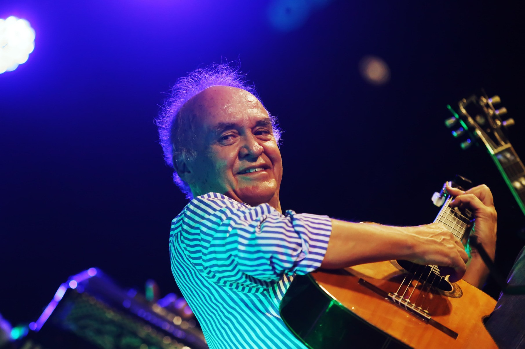 Juarez Moreira toca violão e sorri para a câmera