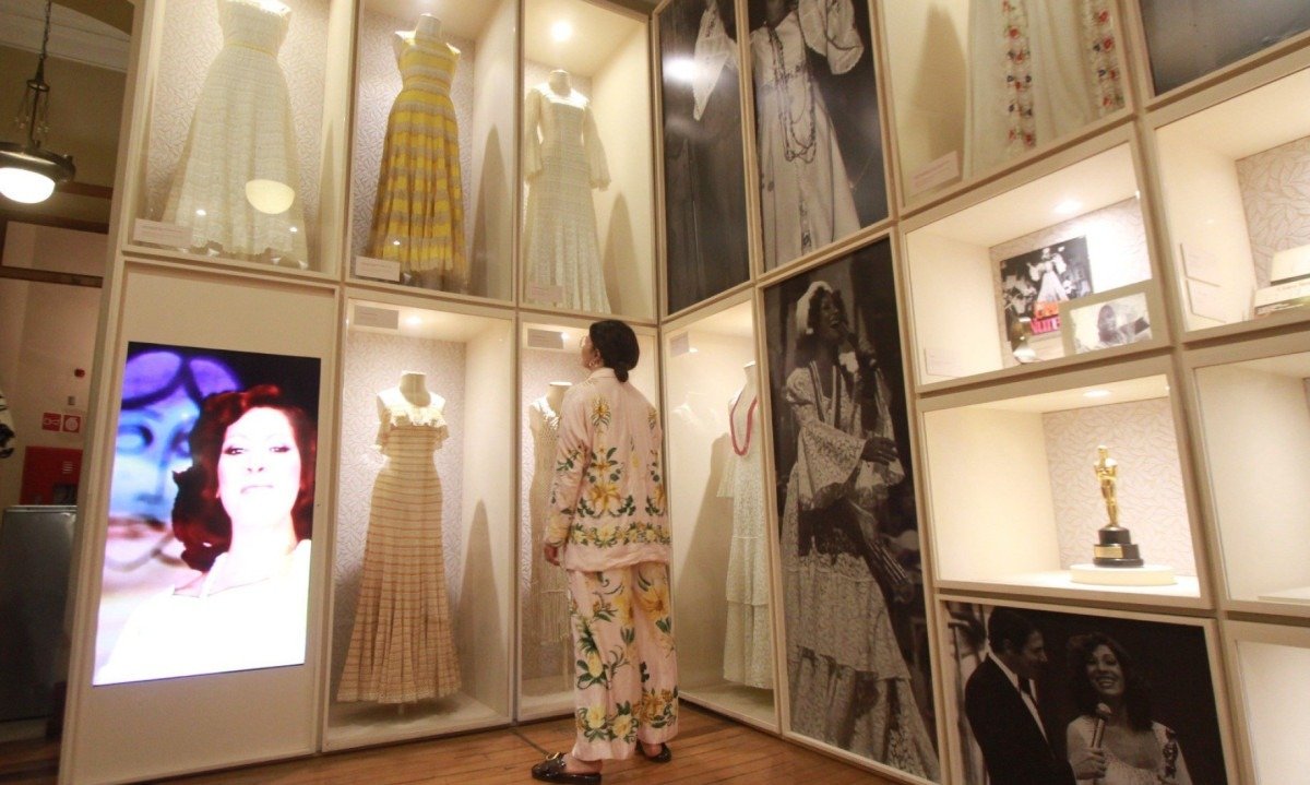 Atriz Emanuelle Araújo diante dos figurinos da cantora Clara Nunes expostos no Museu da Moda de Belo Horizonte