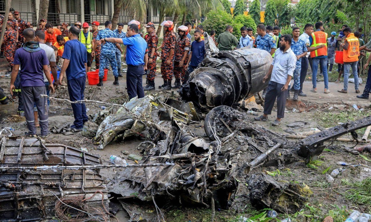 Corpo de bombeiros e equipe de segurança de Bangladesh realizam uma operação de busca e resgate de vítimas da queda de um jato de treinamento da Força Aérea sobre uma escola na capital, Daca -  (crédito: JUBAIR BIN IQBAL / AFP)
