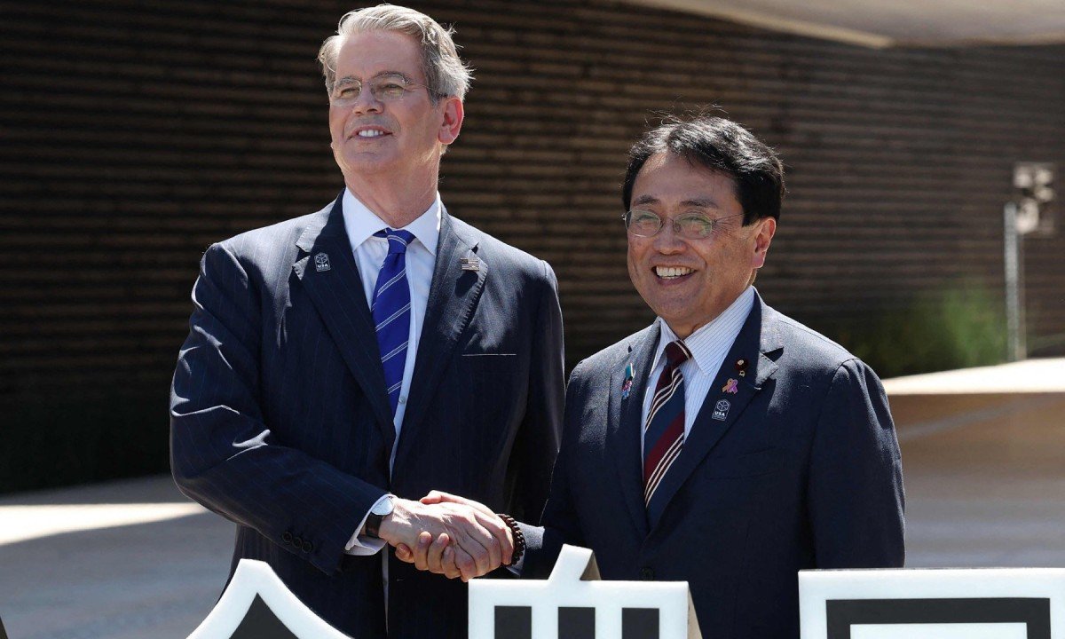 Secretário do Tesouro dos EUA, Scott Bessent (Esq), aperta a mão do ministro da revitalização econômica do Japão e negociador-chefe nas negociações de tarifas comerciais, Ryosei Akazawa (Dir) -  (crédito:  AFP)