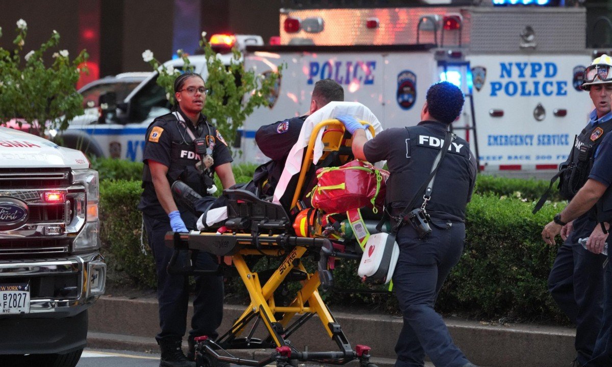Bombeiros de Nova York transportam um policial em uma maca, durante atentado cometido por atirador com rifle, que resultou em quatro mortes
       -  (crédito: TIMOTHY A. CLARY / AFP)