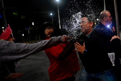 Uma pessoa joga água no rosto de um homem que apoiava o ex-presidente brasileiro Jair Bolsonaro durante um protesto em defesa da soberania nacional após tarifas e sanções comerciais impostas pelo governo dos EUA ao Brasil, perto do consulado dos EUA no Rio de Janeiro, Brasil, em 1º de agosto de 2025 -  (crédito: Mauro Pimentel/AFP)