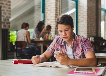 Jovem estuda usando caderno, livros, tabblet e celular para revisão de conteúdo e preparação para provas, sendo que especialistas alertam para crescimento da técnica 'Brain Rot', entre estudantes cada vez mais novos -  (crédito: Freepik)