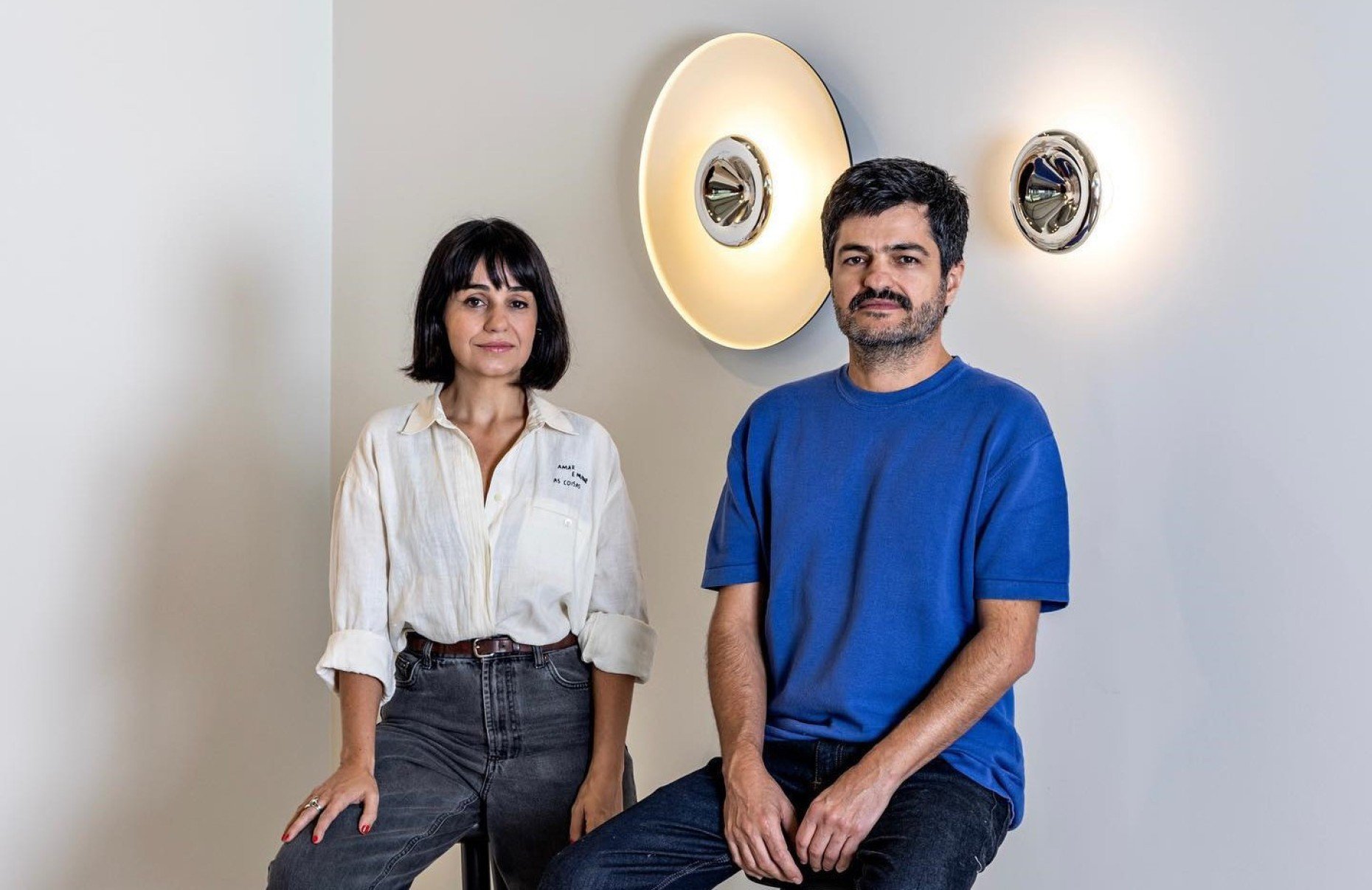 Susana Bastos e Marcelo Alvarenga, figurinistas do Grupo Corpo, estão lado a lado e olham para a câmera 