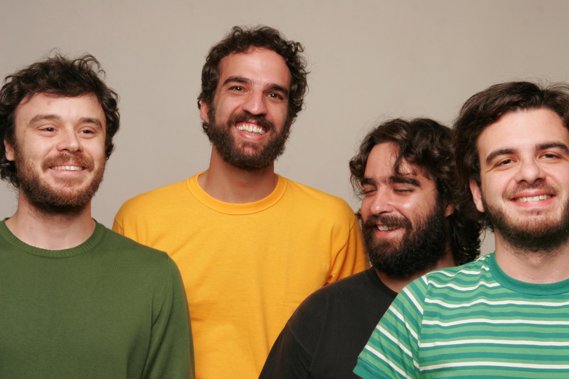 Os quatro músicos da banda Los Hermanos estão lado a lado e olham para a câmera sorrindo