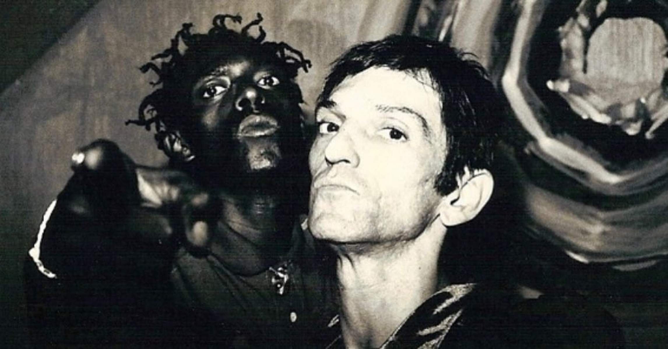 O rapper Sabotage e o cantor Paulo Miklos, lado a lado, olham para a câmera