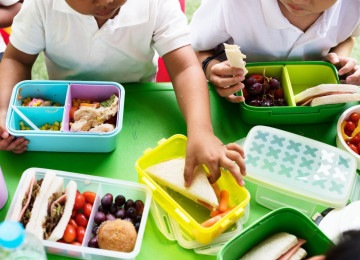 Duas crianças, durante o intervalo na escola, estão na mesa para o lanche, alertando sobre a importância da inclusão também no momento de alimentação, uma vez que os portadores de TEA tem várias restrições alimentares -  (crédito: Freepik)