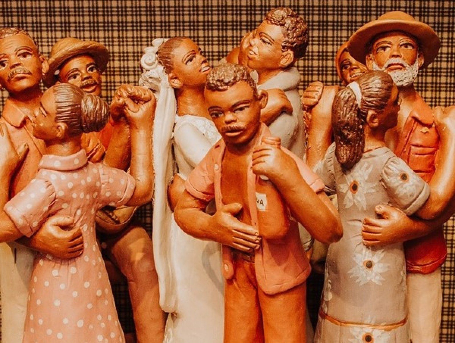 Bonecos de barro, com casal de noivos ao centro, em escultura que remete a festa de casamento