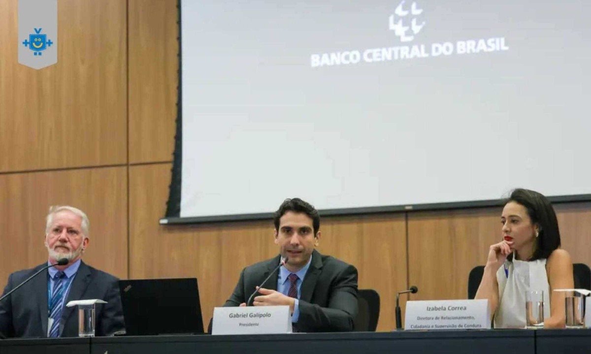 Autoridades do Banco Central do Brasil durante coletiva de imprensa. Na foto, três representantes estão sentados à mesa, com microfones e nomeações à frente. Ao centro, Gabriel Galípolo, presidente do BC, fala ao público. -  (crédito: Reprodução Agência Brasil)