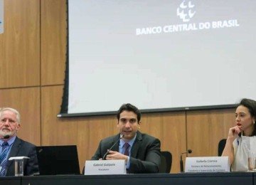 Autoridades do Banco Central do Brasil durante coletiva de imprensa. Na foto, três representantes estão sentados à mesa, com microfones e nomeações à frente. Ao centro, Gabriel Galípolo, presidente do BC, fala ao público. -  (crédito: Reprodução Agência Brasil)
