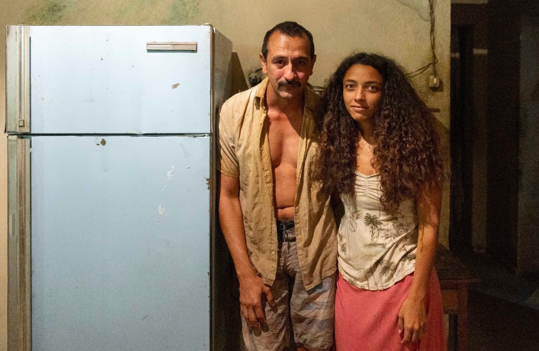  Atores Irandhir Santos e Alice Carvalho, ao lado de geladeira, como o casal Tião Galinha e Joaninha na novela 'Renascer', na Globo