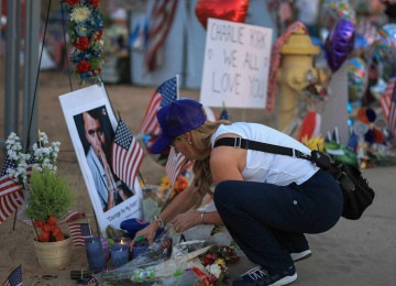 Mulher acende vela em visita o memorial improvisado para Charlie Kirk do lado de fora da sede da Turning Point USA -  (crédito: JOE RAEDLE / GETTY IMAGES NORTH AMERICA / Getty Images via AFP)