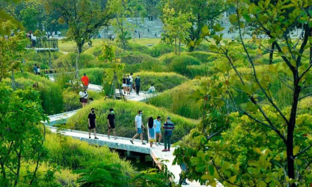 Parque em cidade-esponja; durante periodo de seca, áreas verdes são frequentadas pelas pessoas, que passam por emaranhado de trilhas e passarelas cercadas por pequenos lagos e muito verde