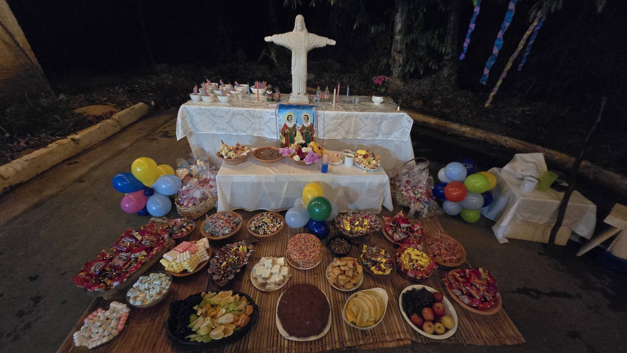 Próximo à mata, o congá (altar) tem a imagem de Oxalá abençoado os doces e oferendas aos santos Cosme e Damião
