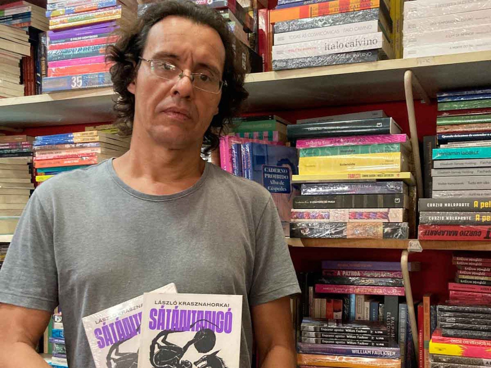 Bruno Zattar, livreiro da Quixote, segura capas de Satantango, de Laszlo Krasznahorkai, livro mais vendido, desde 2022, da livraria na Rua Fernandes Tourinho 