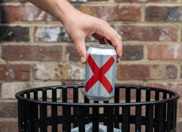 Pessoa descarta latinha de bebida alcoólica em cesto de lixo; imagem meramente ilustrativa -  (crédito: imagem gerada por inteligência artificial/acervo Estado de Minas)