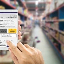 Checklist digital ajuda a otimizar auditorias e inspeções no PDV -  Human using Mobile Phone with white screen on Department store blurred background