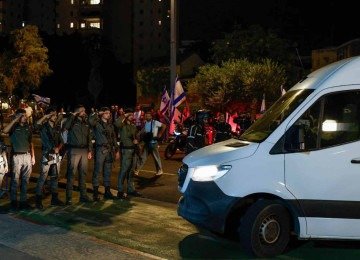 Soldados israelenses saúdam veículos transportando os corpos de quatro pessoas entregues após cessar-fogo e acordo de troca de prisioneiros entre Israel e facções palestinas em Gaza, chegando ao Centro Nacional de Medicina Forense em Tel Aviv em 13 de outubro de 2025 -  (crédito: Jalaa MAREY / AFP)