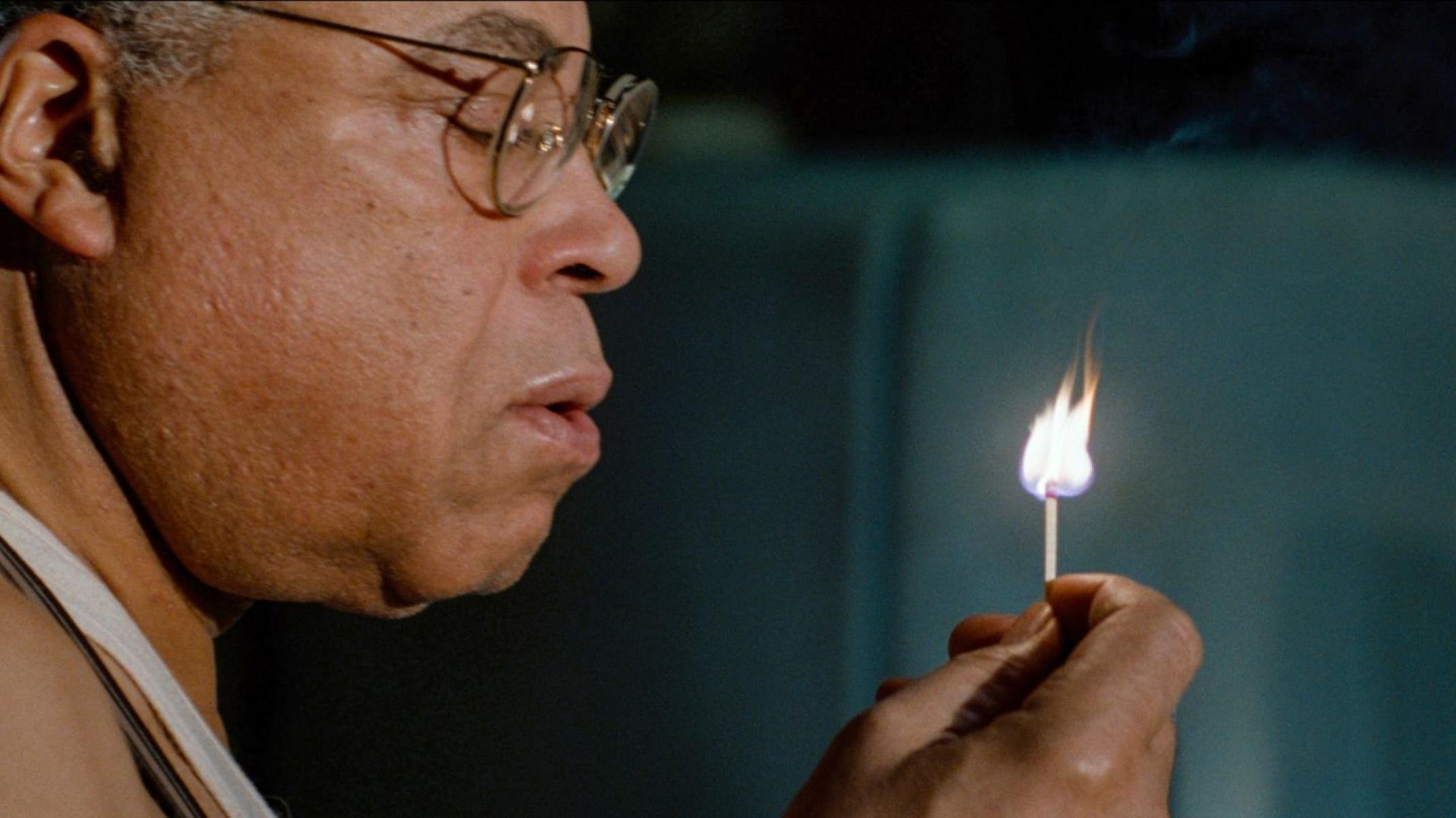 Ator James Earl Jones está de perfil, segurando fósforo aceso, em cena do filme A aniquilação de Fish