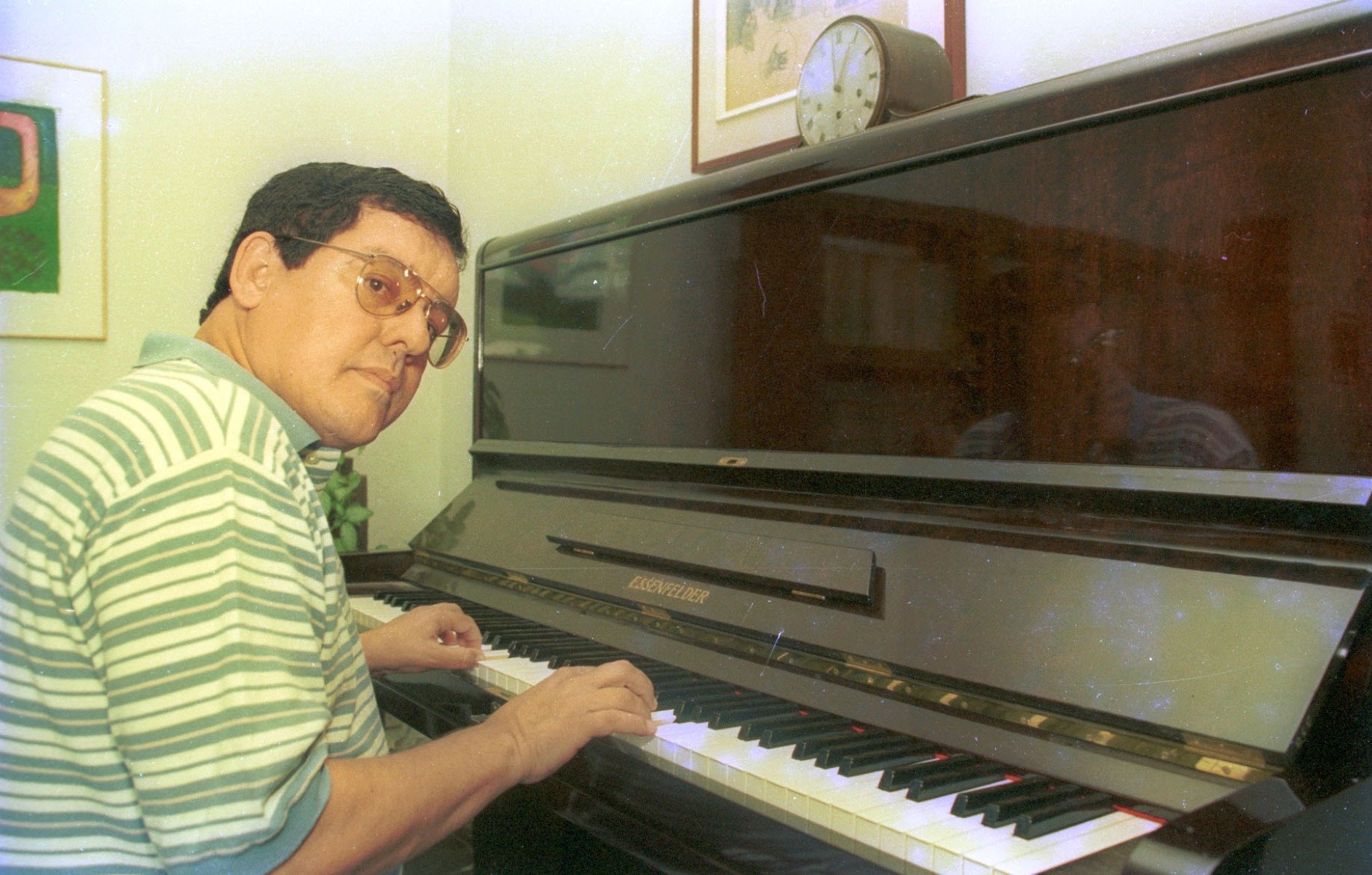 Compositor Fernando Brant toca piano e olha para o lado