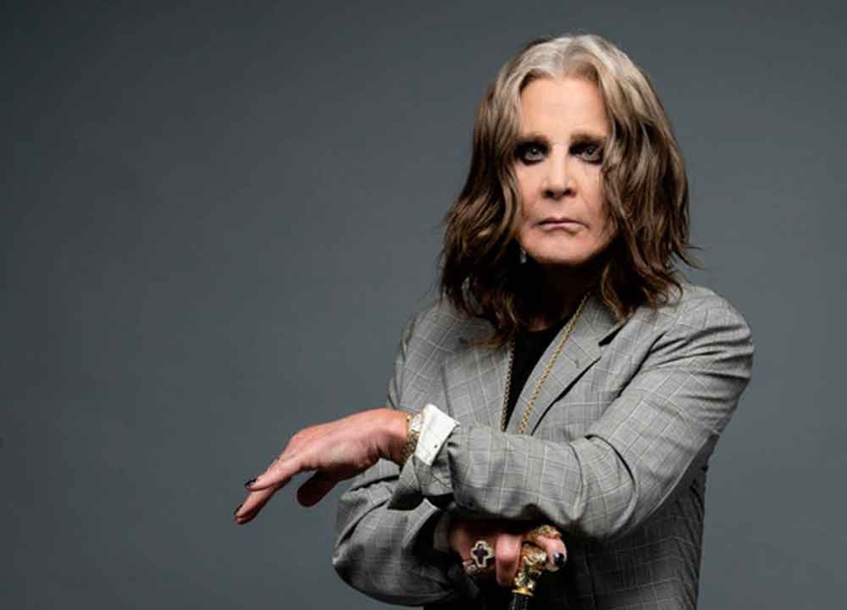 Ozzy Ousborne est&aacute; de lado, segurando bengala e olhando para a c&acirc;mera