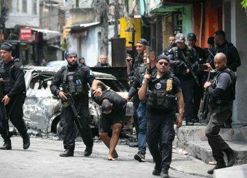 Policiais escoltam um suspeito preso durante a Operação Contenção 
para fora da favela Vila Cruzeiro, no complexo da Penha no Rio de Janeiro -  (crédito: Mauro PIMENTEL / AFP)