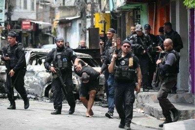 Policiais escoltam um suspeito preso durante a Operação Contenção 
para fora da favela Vila Cruzeiro, no complexo da Penha no Rio de Janeiro -  (crédito: Mauro PIMENTEL / AFP)