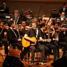 De tênis e camiseta, Lô Borges canta rodeado pela Filarmônica. Foi o convite que mais o emocionou após o 'chamado' de Bituca para gravar 'Clube da esquina' -  (crédito: JPSofranz/Divulgação)