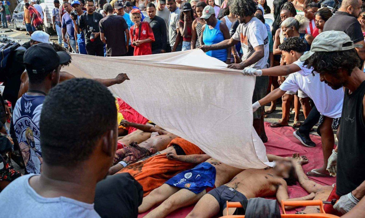Pessoas cobrem corpos enfileirados na Praça São Lucas, na favela Vila Cruzeiro, no complexo da Penha, no Rio de Janeiro, Brasil, em 29 de outubro de 2025, após a Operação Contenção -  (crédito:  PABLO PORCIUNCULA / AFP)