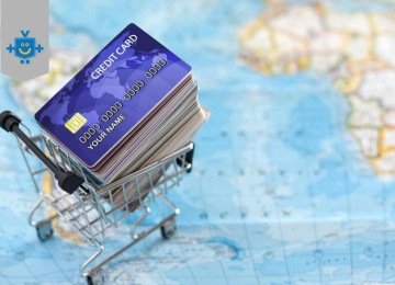 Cartões de crédito empilhados em um carrinho de compras sobre um mapa-múndi, representando o uso de milhas e recompensas para viagens. -  (crédito: Reprodução Educando seu Bolso)