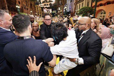 Homem (C) acusado de agredir a estrela pop Ariana Grande sendo contido por seguranças enquanto a colega de elenco Cynthia Erivo (3ª da esquerda) reage na estreia do filme 'Wicked: For Good' em Singapura -  (crédito: STR / THE STRAITS TIMES / AFP)