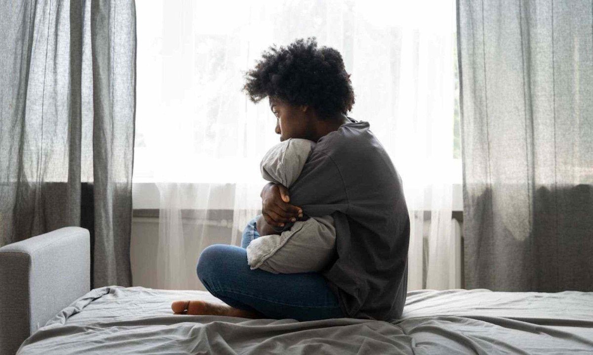 Jovem triste sentada na cama abraçada ao travesseiro; jovens enfrentam bullying e violência em tempos de redes sociais -  (crédito: Freepik)