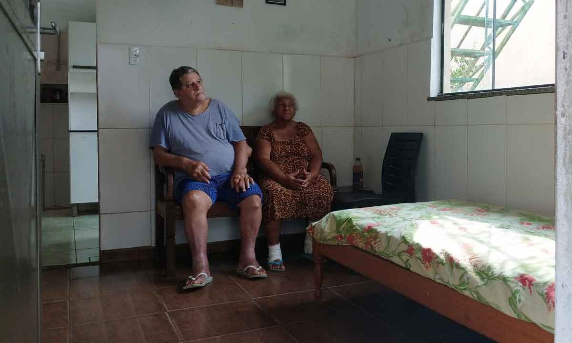 Paulo Roberto e Maria de Fátima, pais do pianista Moisés Mattos, estão sentados lado a lado em cômodo de sua casa humilde em Juiz de Fora