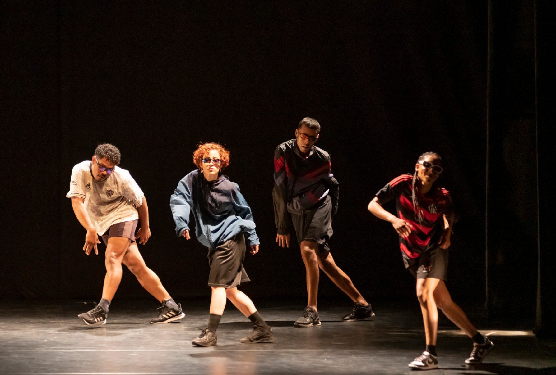 Quatro bailarinos do Corpo Cidadão dançam lado a lado no palco