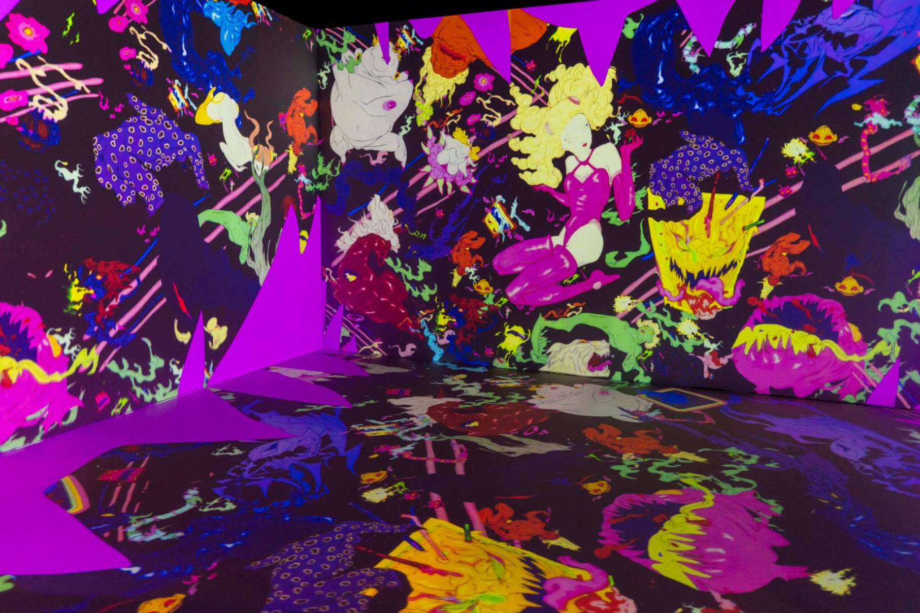  Sala imersiva da exposição de Yoshitaka Amano tem fortes tons rosa, roxos e amarelos, figura feminina com maiô sensual de cabelos louros e criaturas semelhantes a extraterrestres 