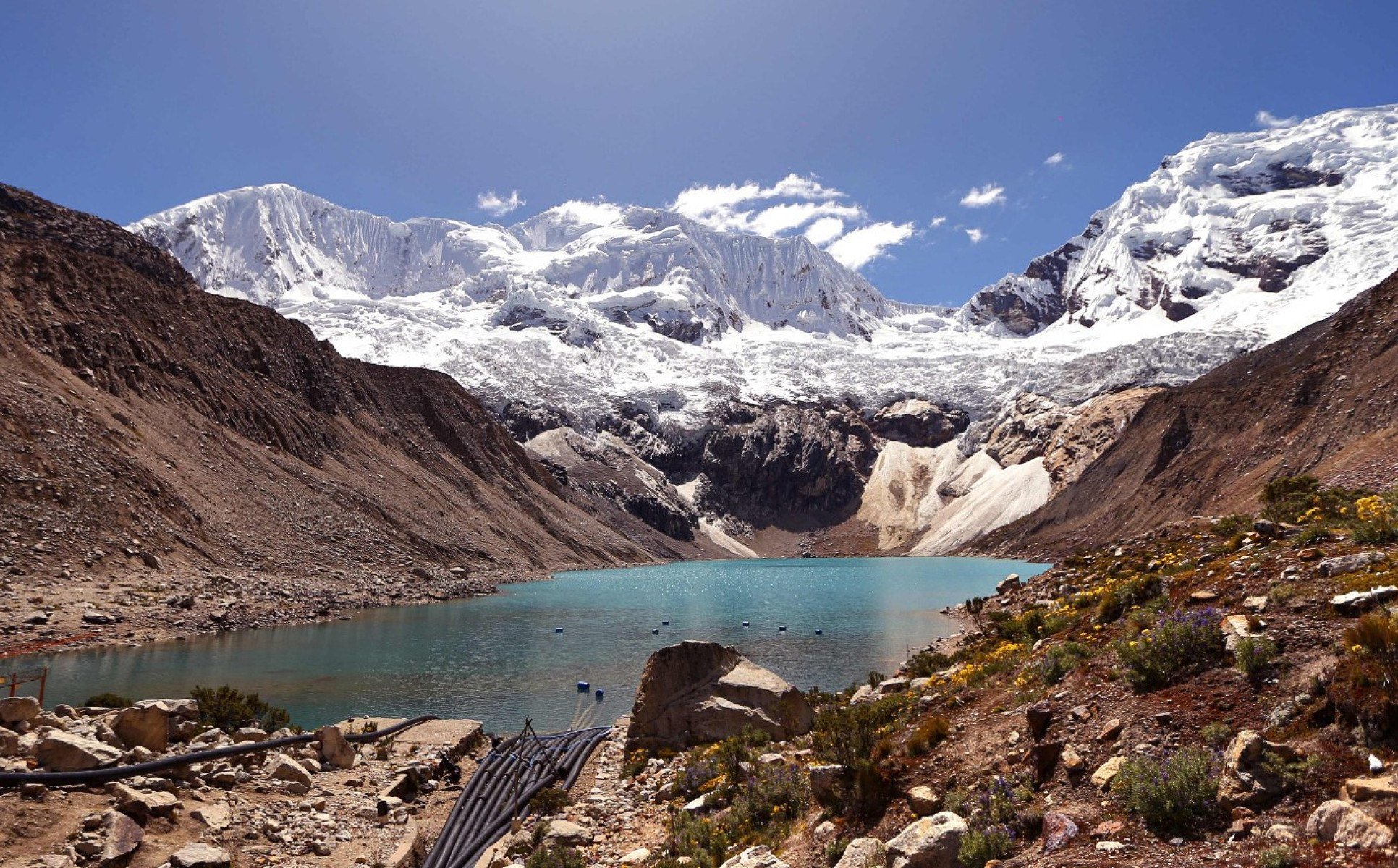 Lago tem ao fundo montanha cheia de neve no Parque de Huascaran, no Peru, em dia ensolarado