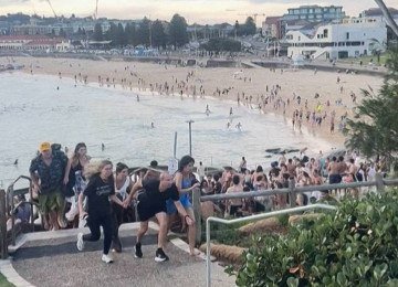 Pessoas correm durante tiroteio na praia de Bondi, em Sydney, na Austrália -  (crédito: Mike Ortiz/AFP)