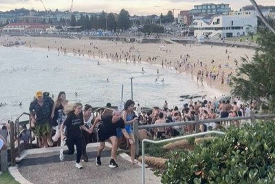Pessoas correm durante tiroteio na praia de Bondi, em Sydney, na Austrália -  (crédito: Mike Ortiz/AFP)