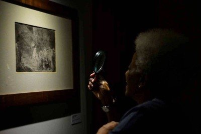 Visitante observa com lupa obra da mostra 'Rembrandt – O mestre da luz e da sombra',  que reúne 69 trabalhos do artista em água-forte e ponta-seca -  (crédito: Rodrigo Gavini/divulgação)