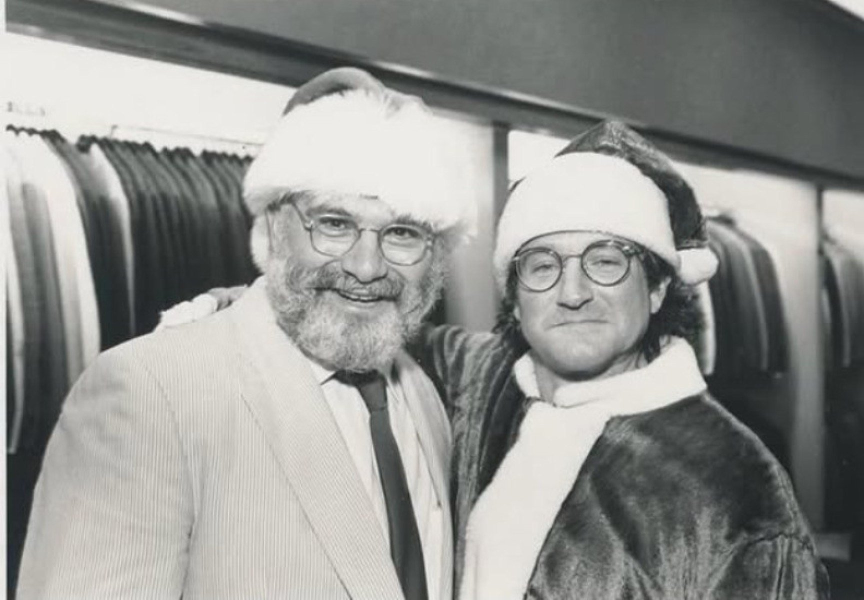 Escritor Oliver Sacks e ator Robin Williams est&atilde;o lado a lado, abra&ccedil;ados, usando gorros de papai noel e sorrindo para a c&acirc;mera