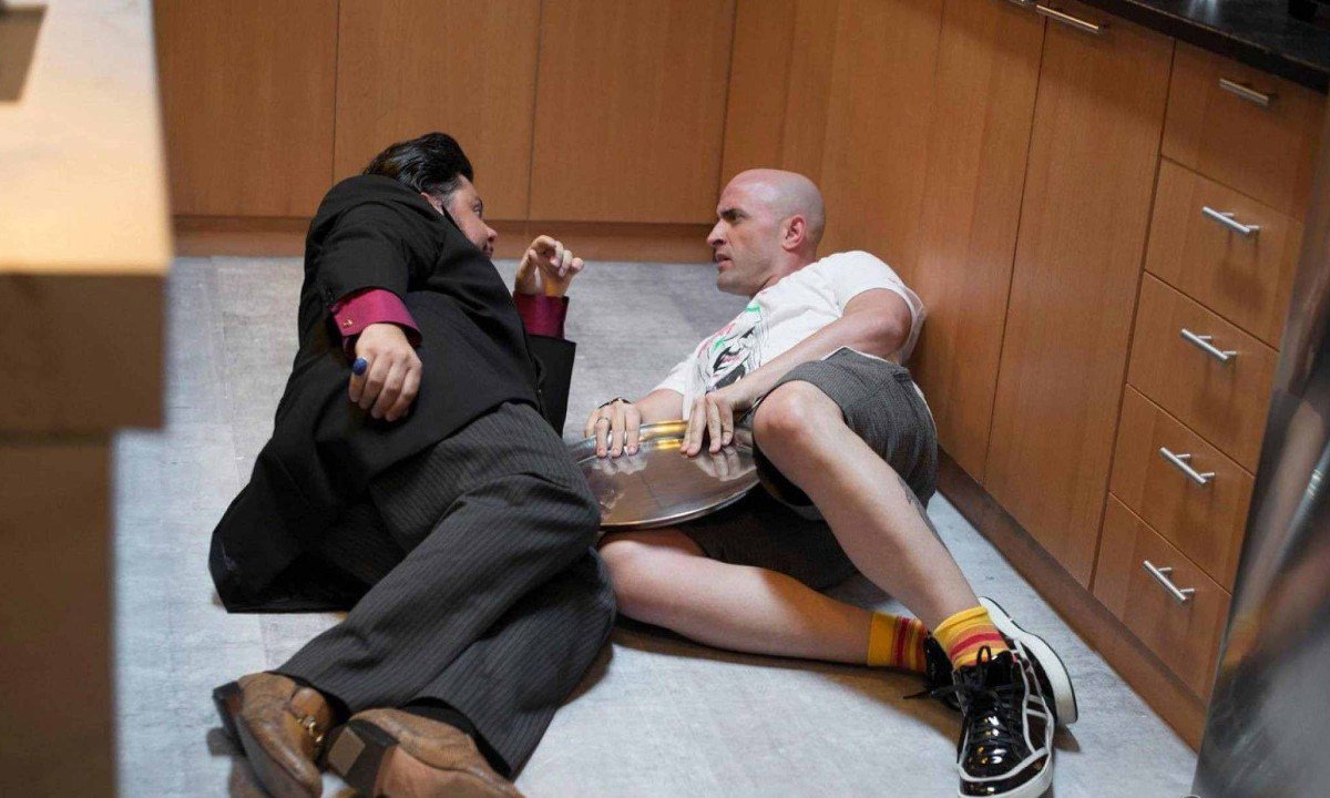 Humoristas Marcus Majella e Paulo Gustavo est&atilde;o se olhando com express&atilde;o assustada, deitados no ch&atilde;o, em cena do filme Vai que cola