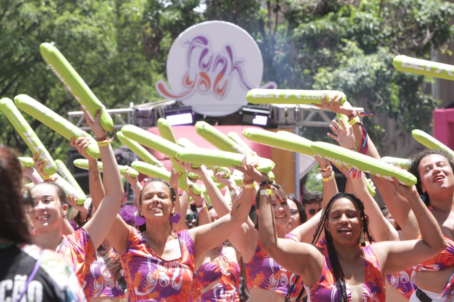  Integrantes do bloco de carnaval Funk You dan&ccedil;am durante o carnaval, erguendo cilindros de espuma verde para o alto