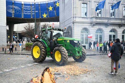 Agricultores posam ao lado de batatas e um trator estacionado em frente ao Parlamento Europeu, durante um protesto de agricultores para denunciar as reformas da Política Agrícola Comum (PAC) e acordos comerciais como o Mercosul, em Bruxelas, em 18 de dezembro de 2025 -  (crédito: NICOLAS TUCAT / AFP)