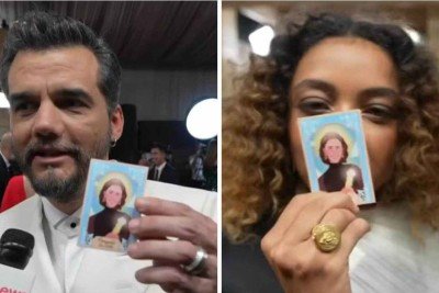 Wagner Moura e Alice Carvalho com 'santinho' de Fernanda Torres no tapete vermelho do Globo de Ouro -  (crédito: GloboNews / reprodução)