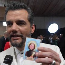 Wagner Moura segura santinho com ilustração de Fernanda Torres no tapete vermelho do Globo de Ouro, em transmissão da GloboNews  -  (crédito: Reprodução)