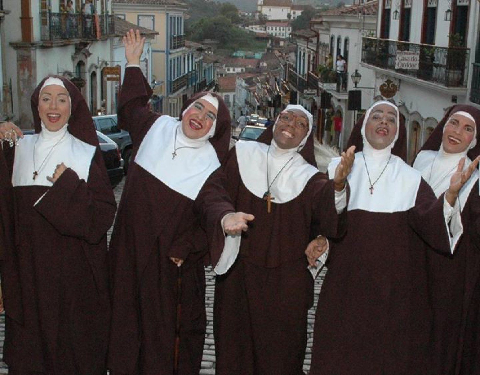 Vestidos como freiras, atores da pe&ccedil;a Santinhas do pau oco est&atilde;o na rua. Elenco sorri e olha para a c&acirc;mera 
