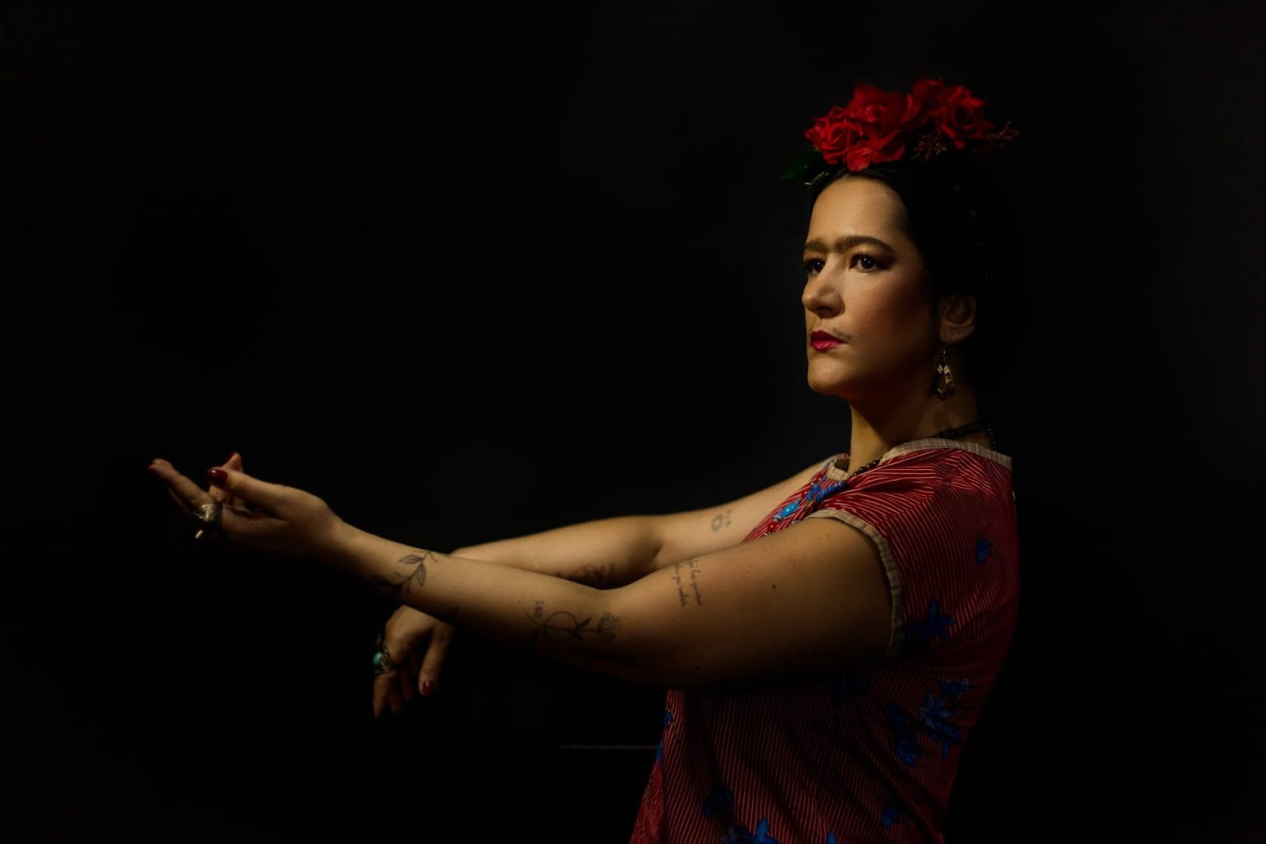 Atriz B&aacute;rbara Oliveira est&aacute; de lado, com os bra&ccedil;os estendidos, caracaterizada como a pintora Frida Kahlo