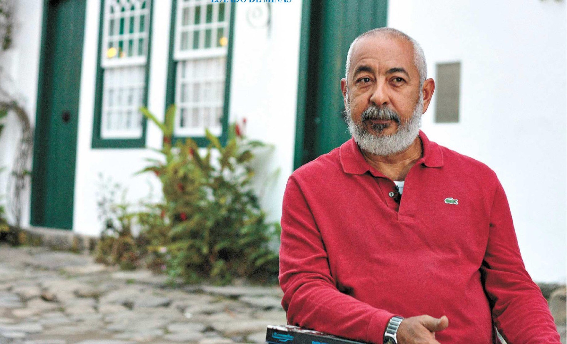 Escritor Leonardo Padura de blusa vermelha, em frente &agrave; casas antigas